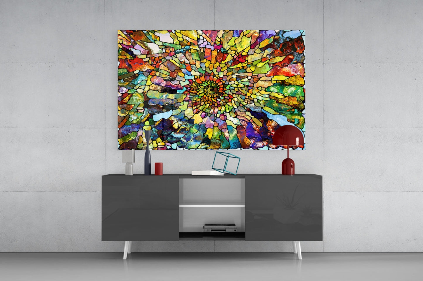 Vibrant multicolored mosaic glass art with concentric spiral pattern displayed above gray media console in modern interior setting.