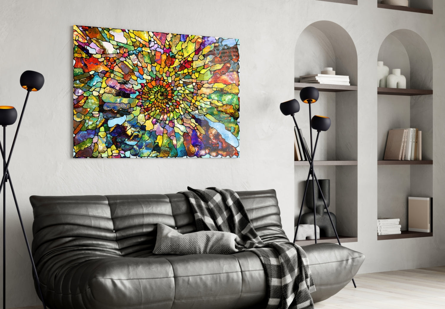 Vibrant multicolored mosaic glass art with concentric circular pattern displayed above black leather sofa in modern living room.