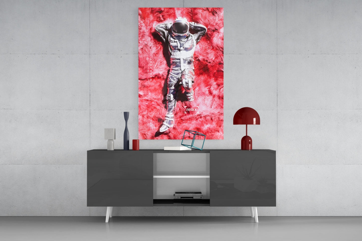 Vibrant pink glass art of a relaxed astronaut displayed above a modern dark console table in a minimalist interior setting.