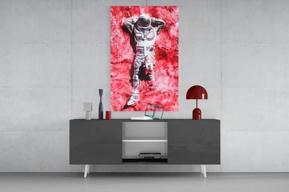 Vibrant pink glass art of a relaxed astronaut displayed above a modern dark console table in a minimalist interior setting.