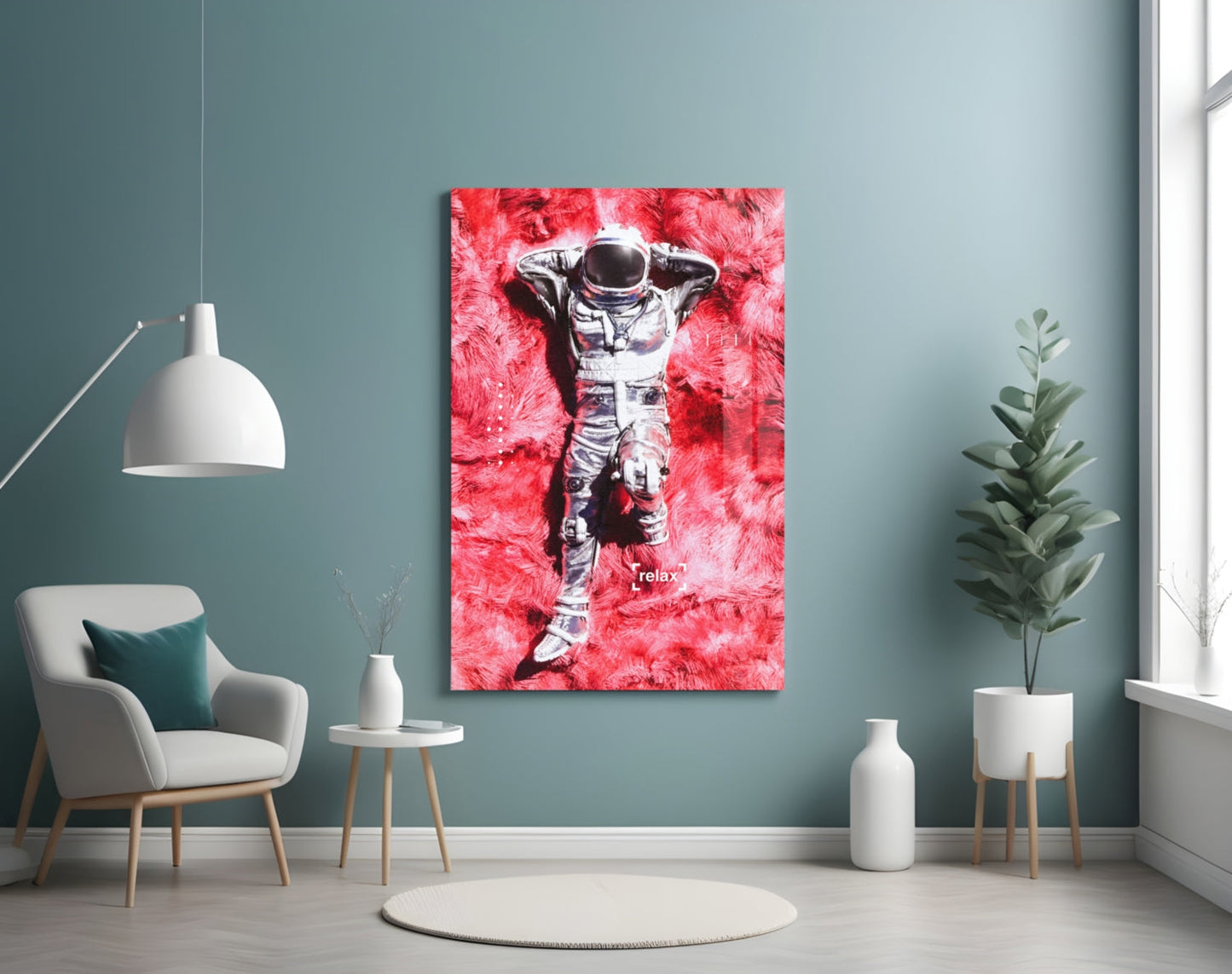 Modern living room interior with muted teal wall displaying vibrant red and white astronaut glass art print centered above white chair and potted plant.
