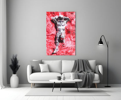 Glass art print of astronaut lying on pink textured background with "relax" text, displayed above white sofa in modern living room.