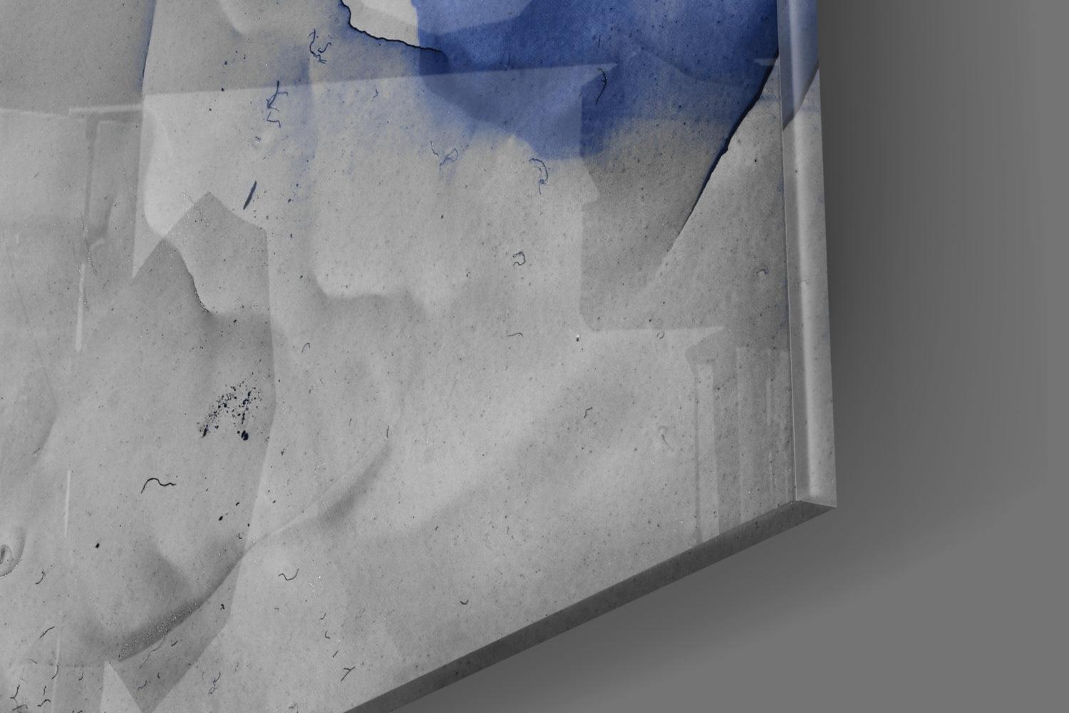 Overhead view of blue marble glass art piece on white concrete surface with water pooling and small marks visible.