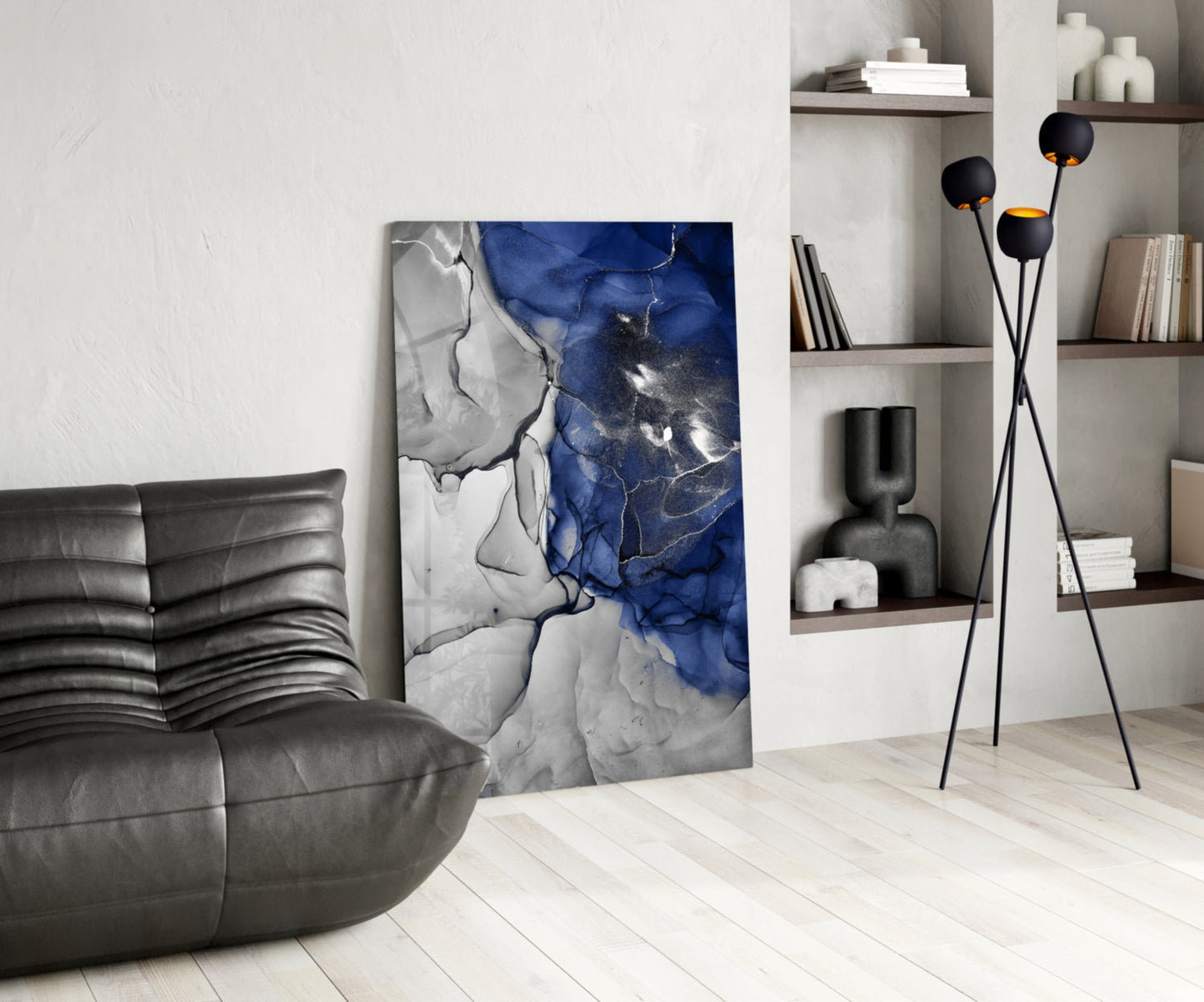 Blue and white marbled glass art panel leaning against wall in modern living room with grey sofa and shelving.