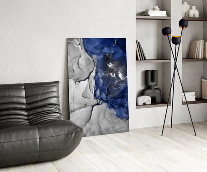 Blue and white marbled glass art panel leaning against wall in modern living room with grey sofa and shelving.