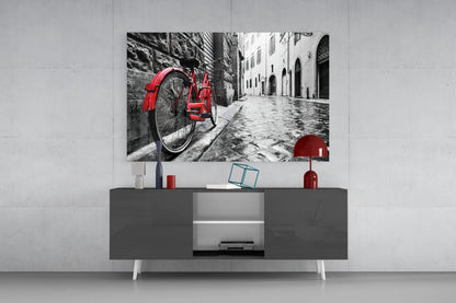 Red bicycle parked on European cobblestone street displayed as wall art above gray media console.