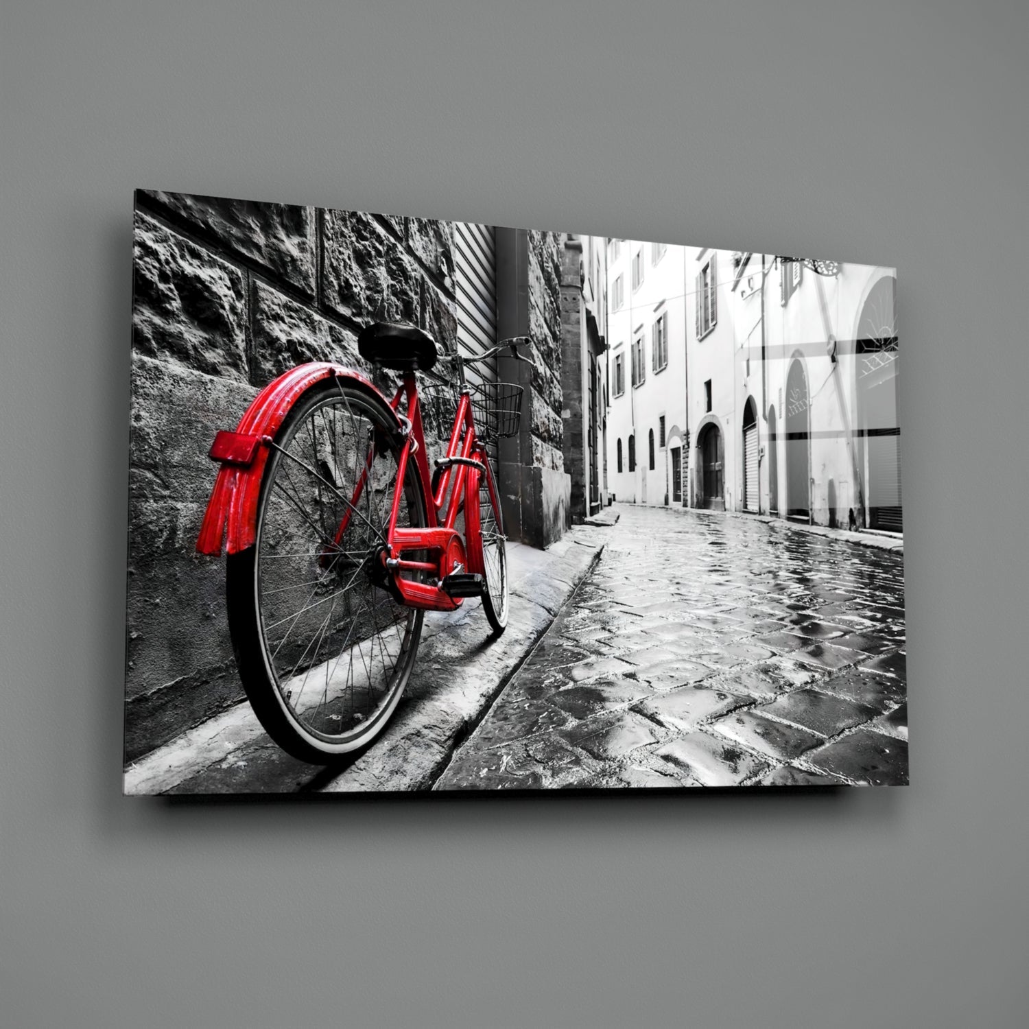 Red vintage bicycle leaning against stone wall in black and white Italian street scene with historic buildings.