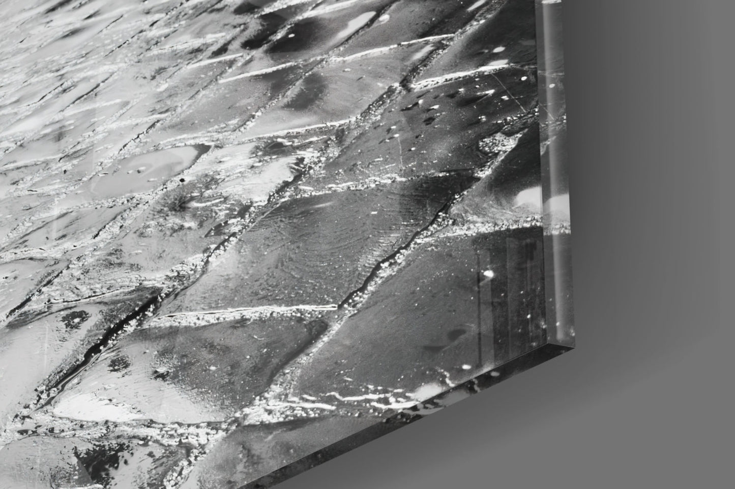 Close-up of textured glass surface with white and gray streaked patterns and a metal frame edge visible on the right side.