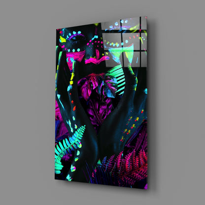 Angled view of neon glass art panel featuring vibrant magenta, cyan, and yellow fluorescent figures and botanical forms against black background.