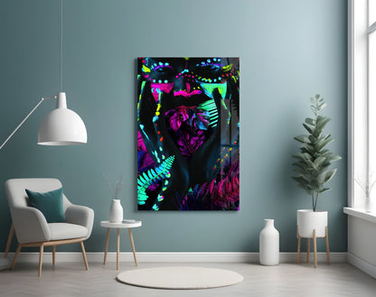 Neon Glances Glass Art displayed on pale blue wall above white chair, showing vibrant magenta, cyan, and yellow abstract botanical forms on black background.