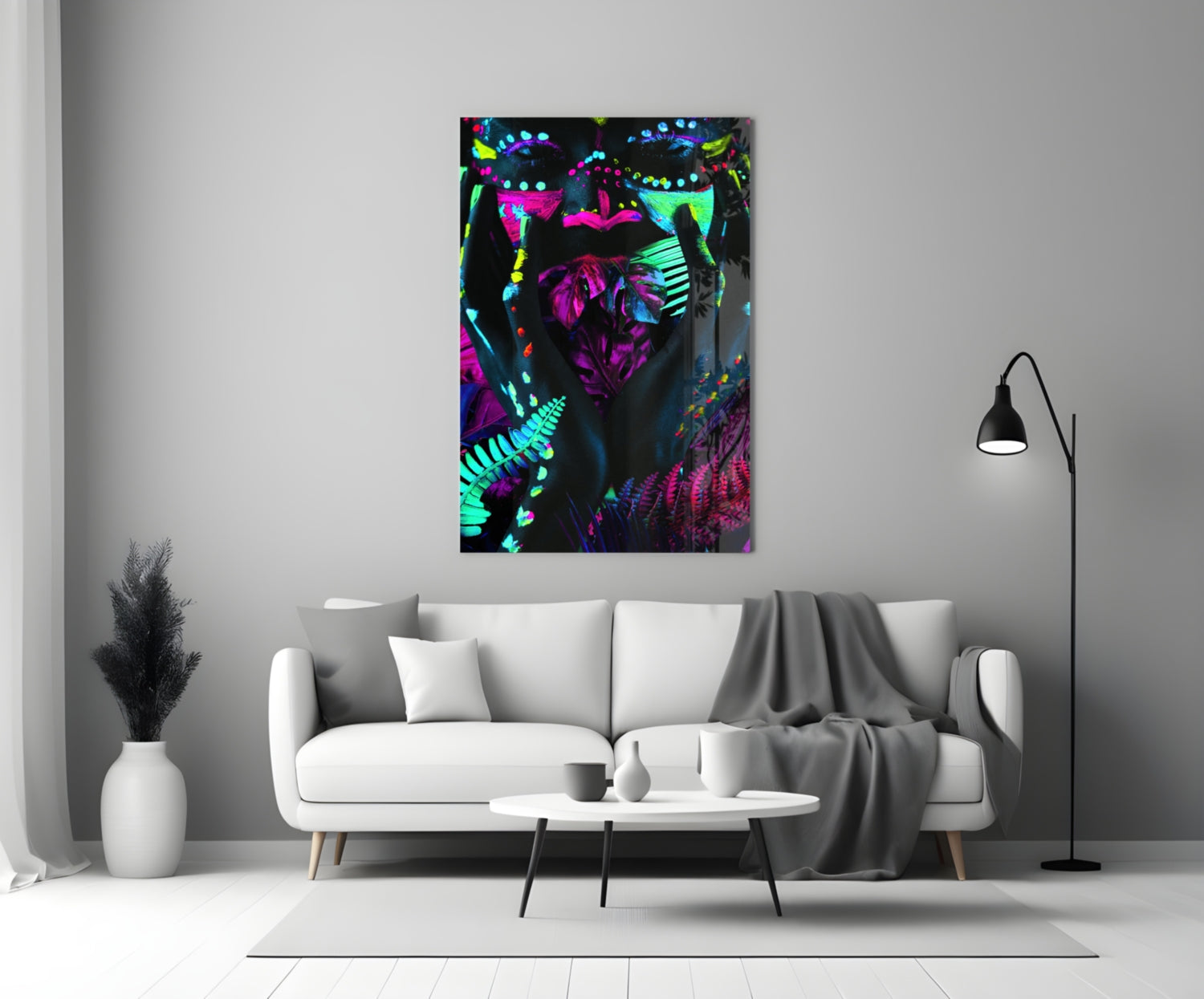 Neon Glances Glass Art displayed above a white sofa in a modern living room interior, showing vibrant magenta, cyan, and yellow fluorescent figures against a dark background.