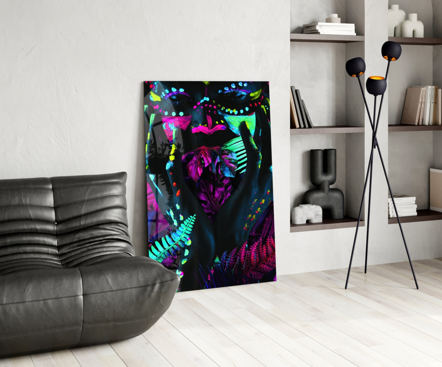 Neon Glances Glass Art displayed in modern living room beside gray leather sofa, featuring vibrant fluorescent pink, cyan, and yellow botanical designs on black background.