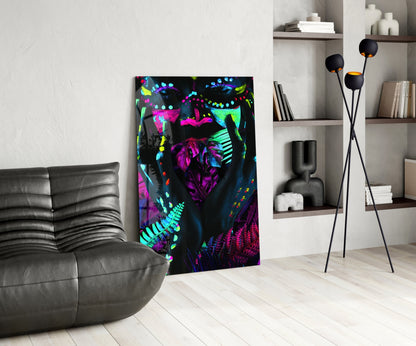 Neon Glances Glass Art displayed in modern living room beside gray leather sofa, featuring vibrant fluorescent pink, cyan, and yellow botanical designs on black background.