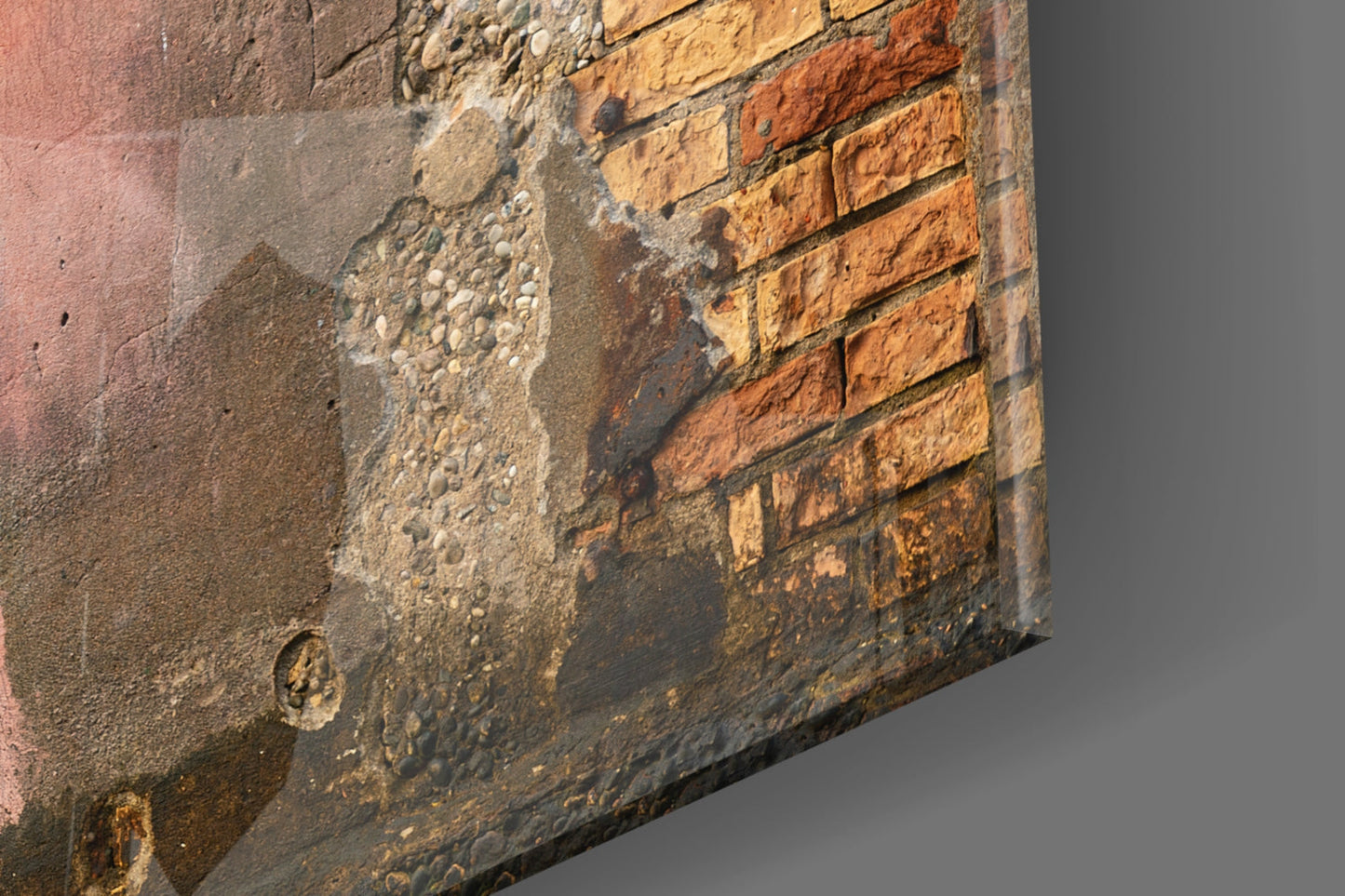 Close-up of weathered brick and concrete wall showing orange and tan bricks with gray mortar and surface deterioration.
