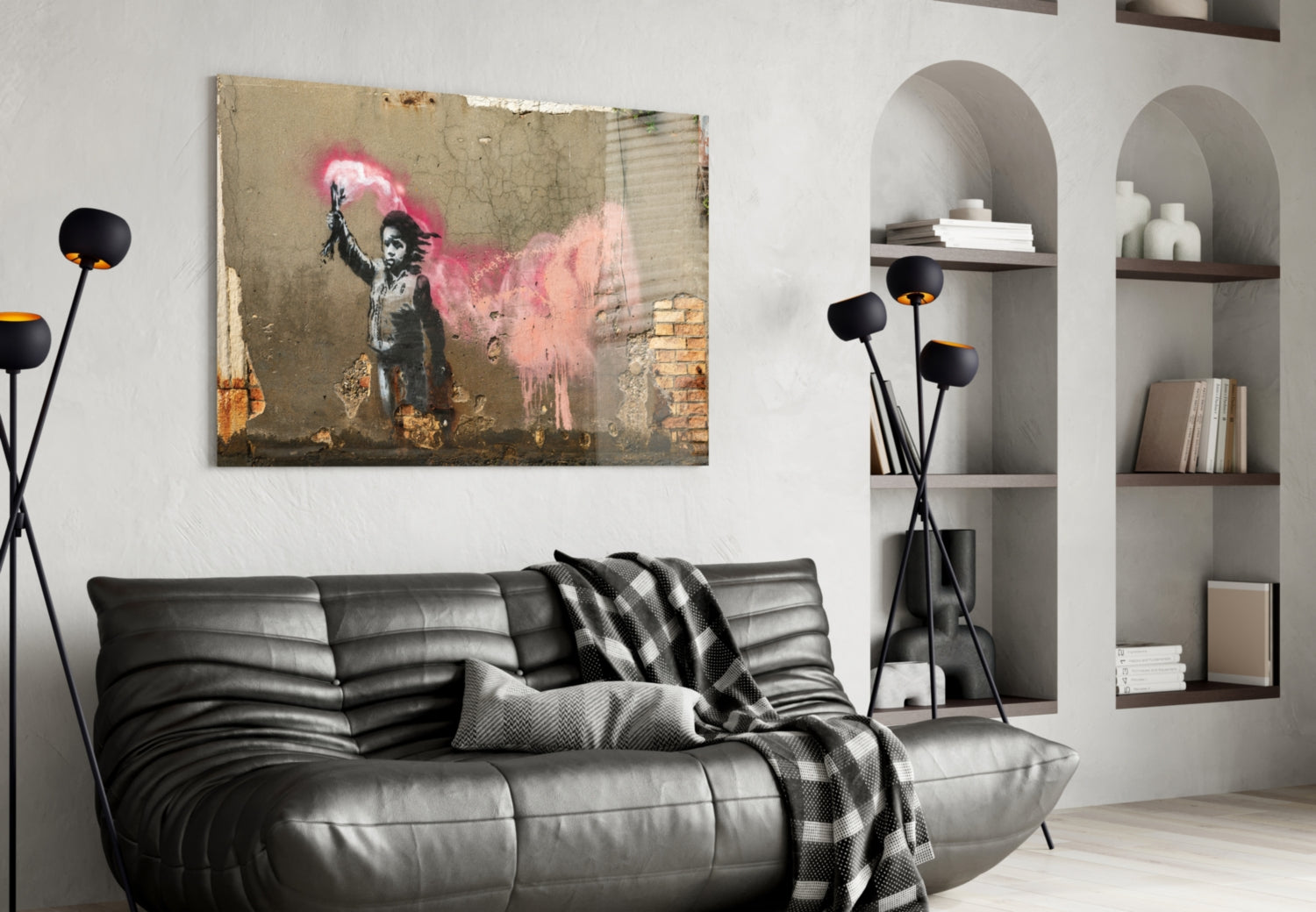 Modern living room with black leather sofa displaying Banksy-style street art print featuring child with pink spray paint above.