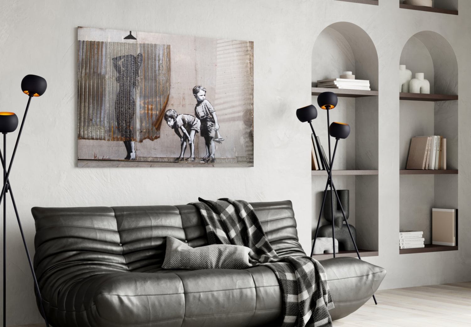 Modern living room with black leather sofa, arched wall alcoves, black floor lamp, and framed street art print above furniture.