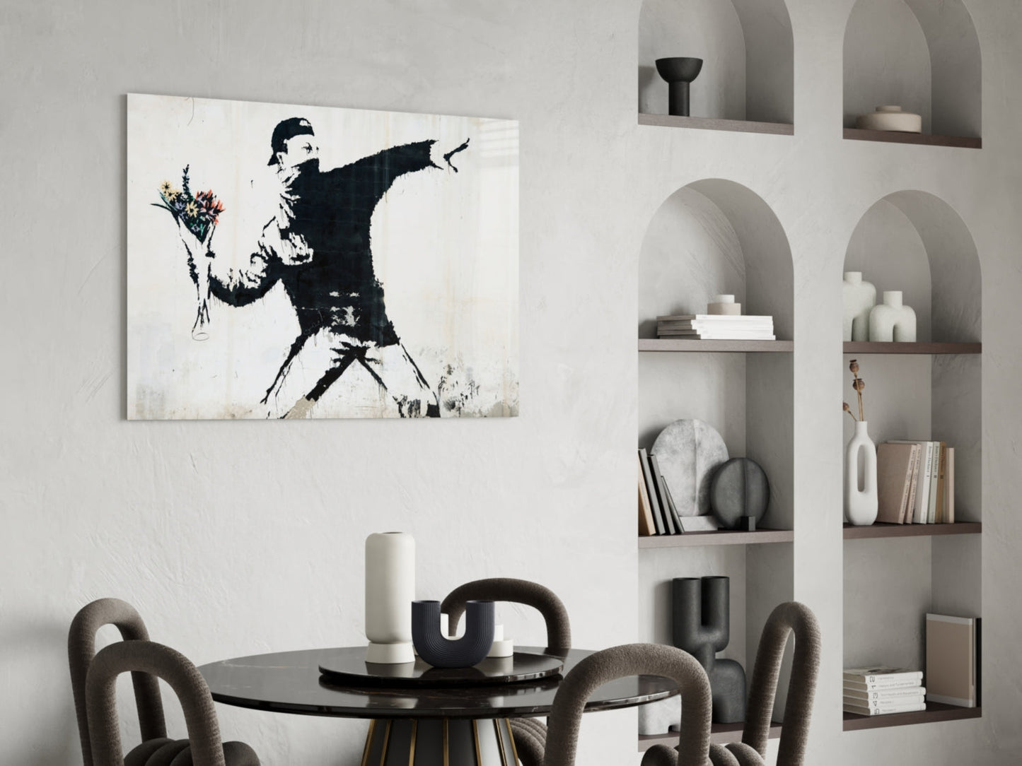 Black and white stencil art of figure throwing flowers on white wall above dining table with chairs and shelving.