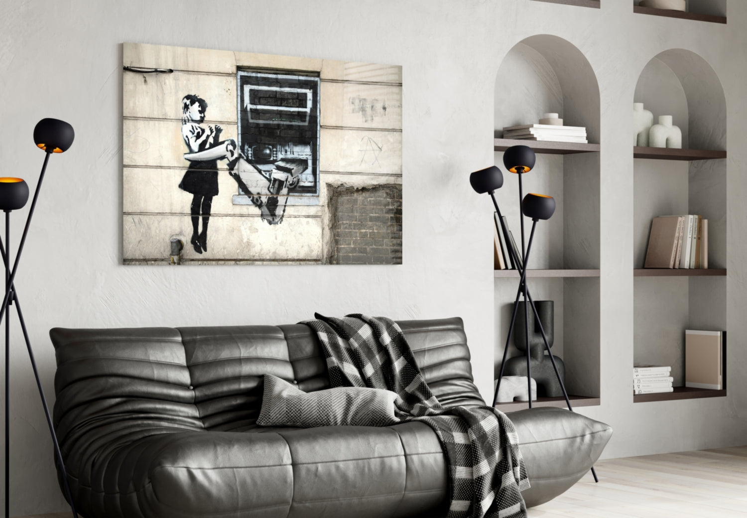 Modern living room with black leather sofa displaying street art canvas featuring stenciled figure and ATM, styled with floor lamp and white built-in shelving.