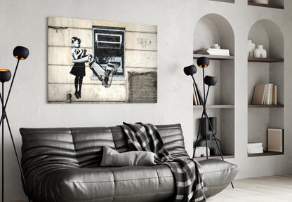 Modern living room with black leather sofa displaying street art canvas featuring stenciled figure and ATM, styled with floor lamp and white built-in shelving.