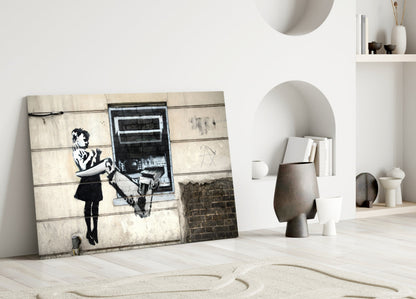Banksy "Girl with Rat" glass art leaning against white wall in minimalist interior with shelving and ceramic vessels.