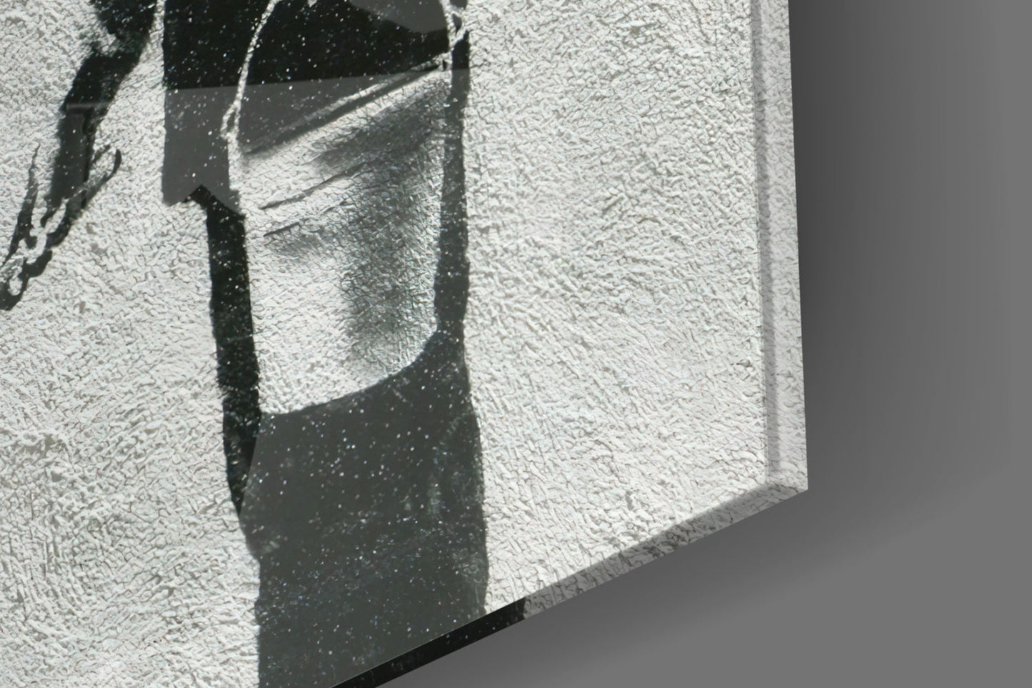 Close-up of textured white glass surface with dark shadow cast by geometric architectural element, showing surface detail and light interplay.