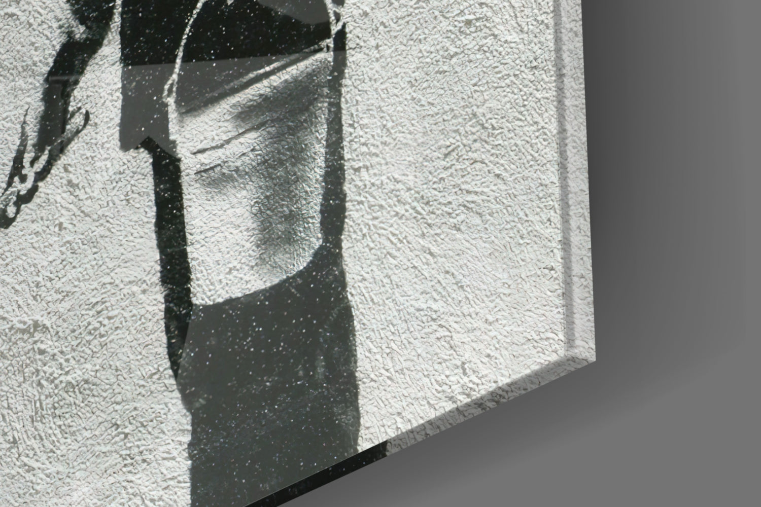 Close-up of textured white glass surface with dark shadow cast by geometric architectural element, showing surface detail and light interplay.