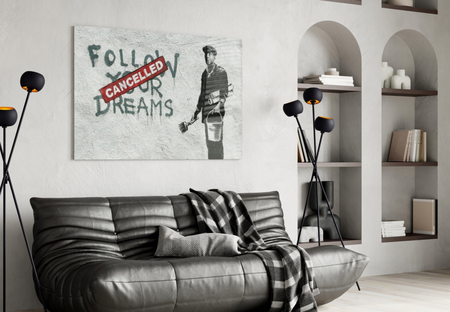 Glass art print displayed above black leather sofa in modern living room with white walls and built-in shelving.