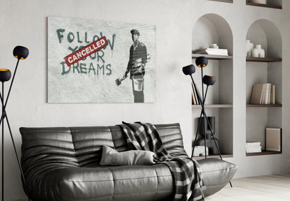 Glass art print displayed above black leather sofa in modern living room with white walls and built-in shelving.