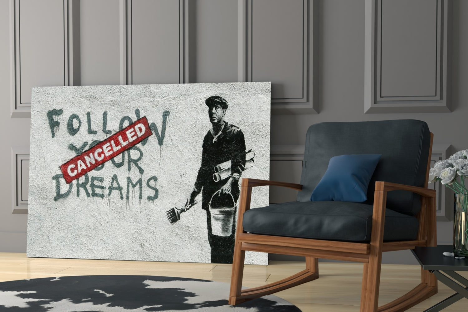 Glass art canvas displaying stenciled figure with bucket and red "CANCELLED" stamp over "FOLLOW YOUR DREAMS" text, positioned in modern interior setting beside wooden chair.