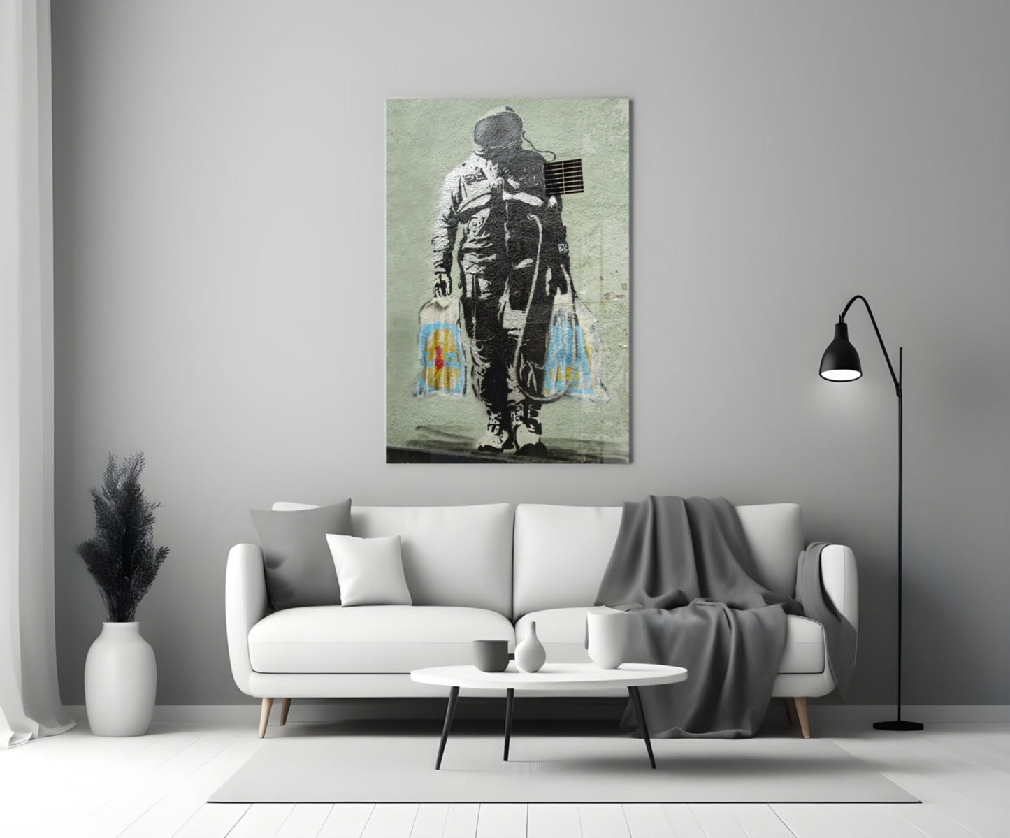 Glass art panel featuring stenciled astronaut with American flag and colorful paint drips displayed above white sofa.