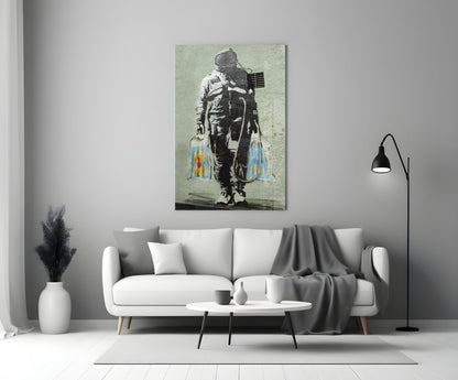 Glass art panel featuring stenciled astronaut with American flag and colorful paint drips displayed above white sofa.