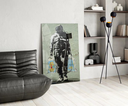 Modern living room featuring stenciled astronaut artwork on pale green glass leaning against white wall beside black leather chair.
