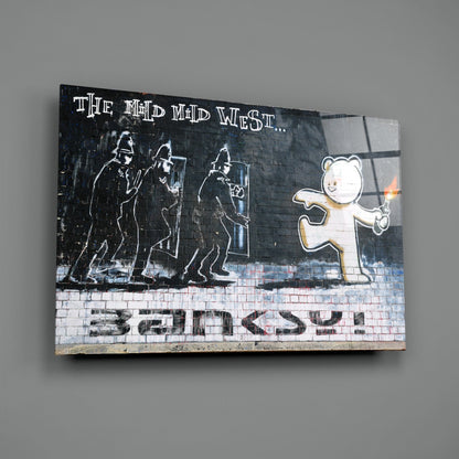 Glass art print featuring stenciled figures and teddy bear with "The Mid West... Banksy" text on brick background.