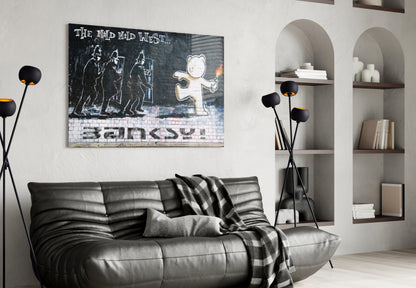Banksy street art print hung above black leather sofa in modern living room with arched shelving and floor lamp.
