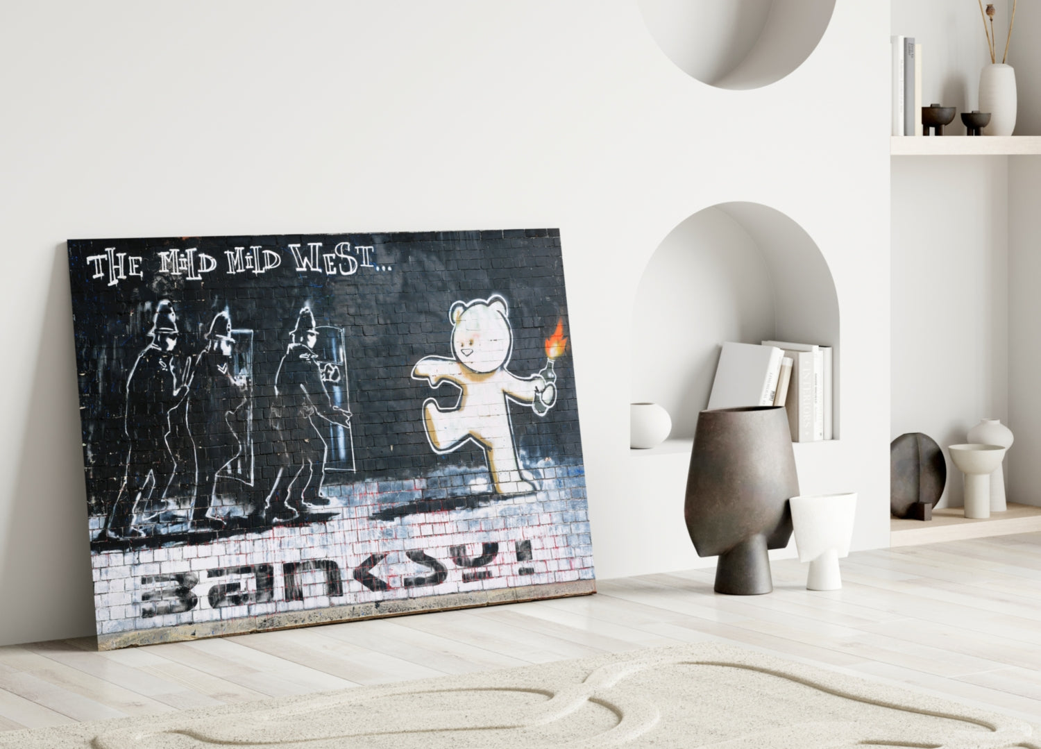 Street art glass panel leaning against white wall displays bear holding torch with police figures and "The Mid Mad West" text on brick background.