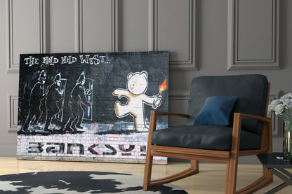 Street art glass panel depicting armed figures and white bear with torch, text "The Mad Mad West" and "Banksy," displayed in modern interior.