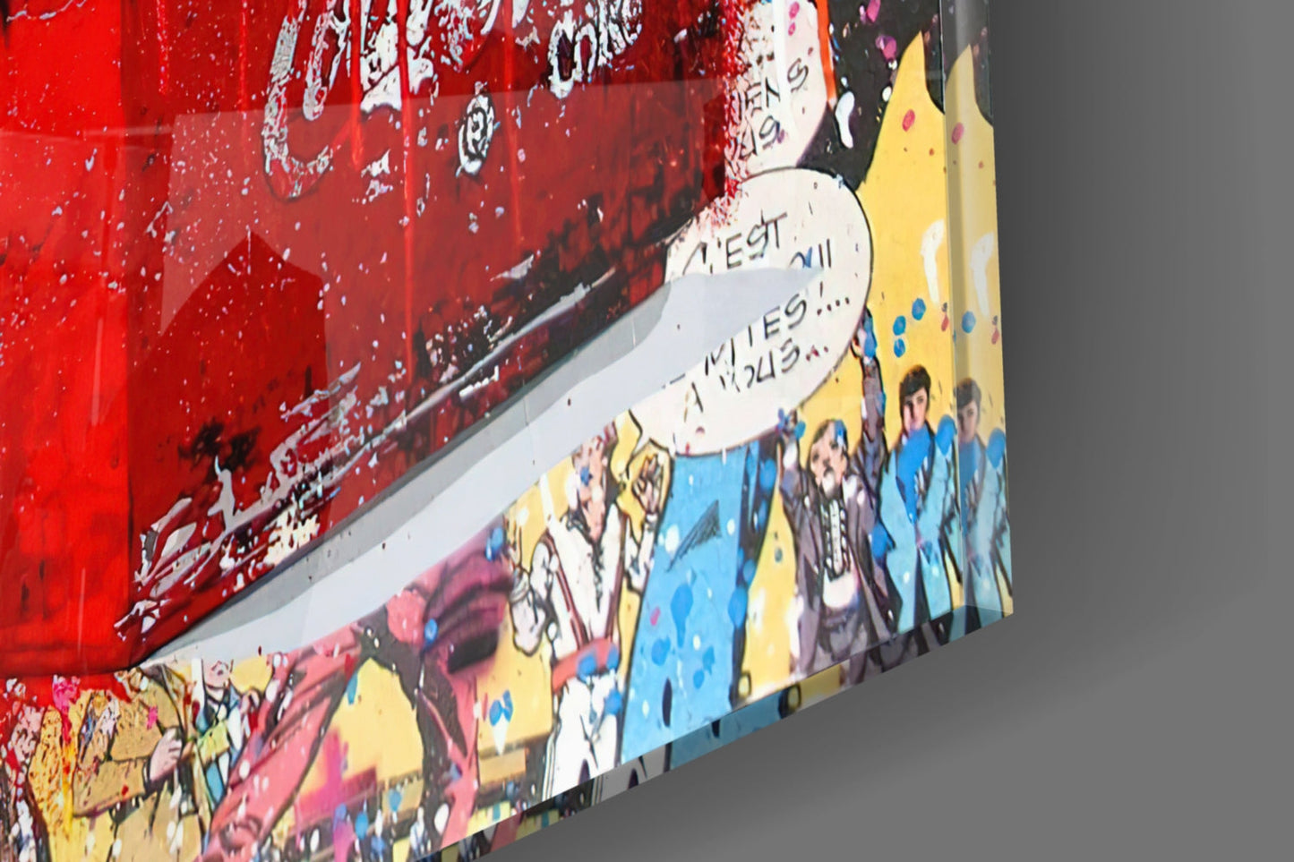 Angled view of colorful glass art panel with red upper section, yellow and blue illustrated characters below, and handwritten French text on white banner.