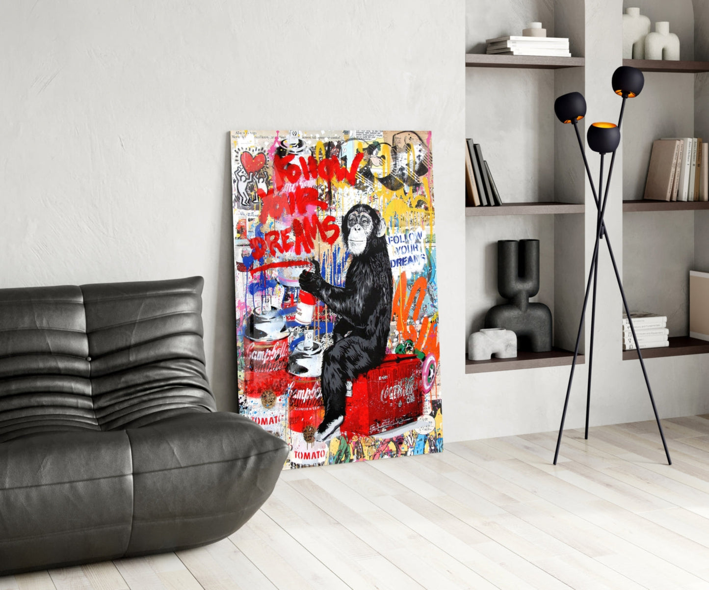 Colorful street art glass panel featuring a chimpanzee with red "Follow Your Dreams" text displayed in modern living room with black leather sofa.