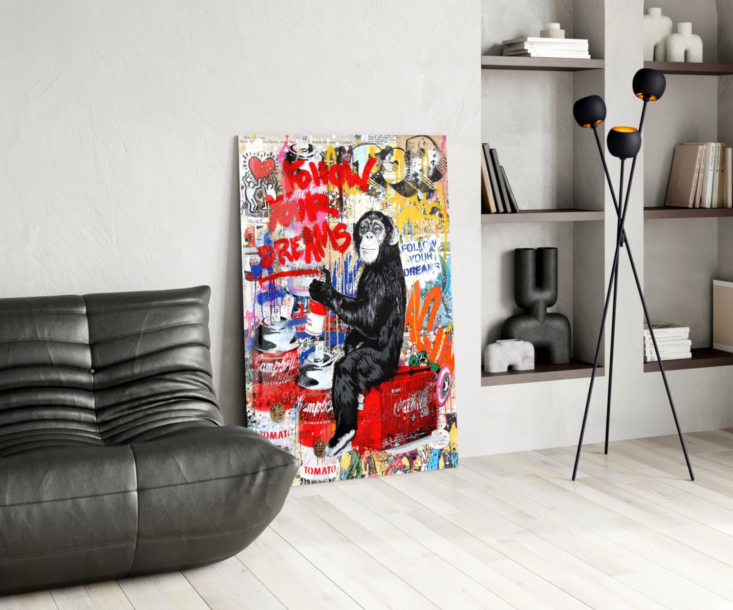 Colorful street art glass panel featuring a chimpanzee with red "Follow Your Dreams" text displayed in modern living room with black leather sofa.