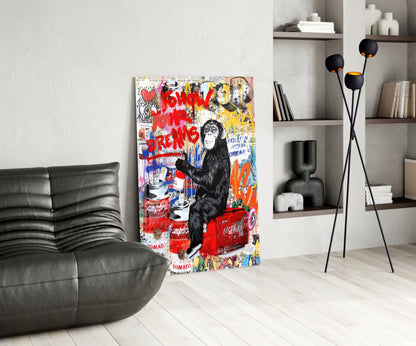 Colorful street art glass panel featuring a chimpanzee with red "Follow Your Dreams" text displayed in modern living room with black leather sofa.