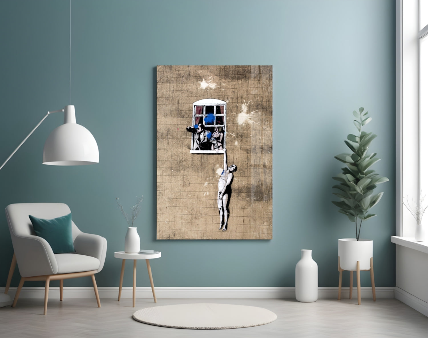 Banksy-style street art canvas on teal wall showing figure hanging from window, styled interior room setting.