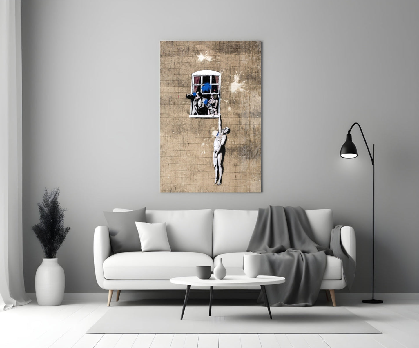 Banksy-style street art print on textured canvas showing figure climbing rope toward window with people inside, displayed above white sofa in modern living room.