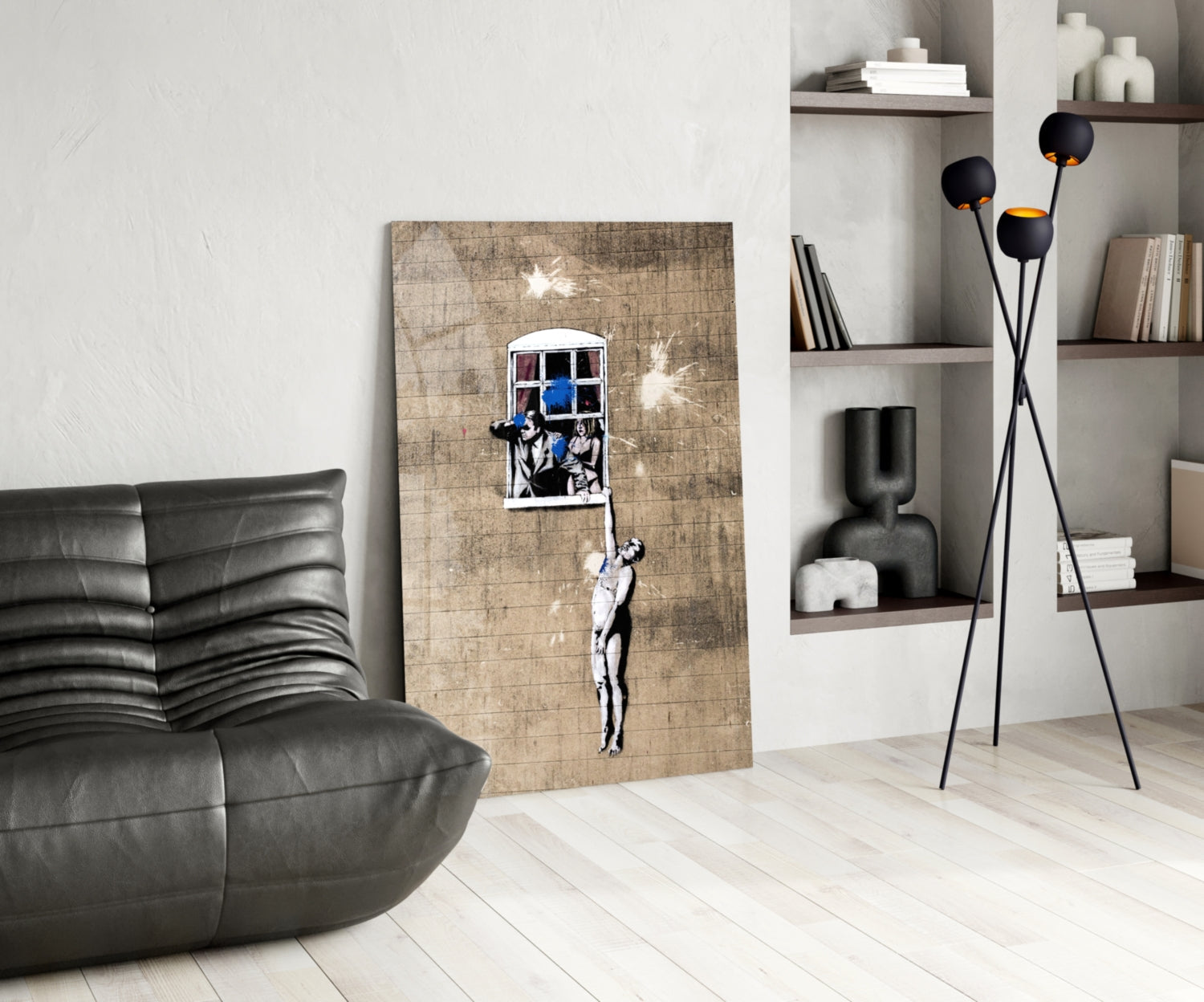 Modern living room interior featuring Banksy-style stencil art on wooden panel of figure reaching toward window with blue sky, displayed against white wall.