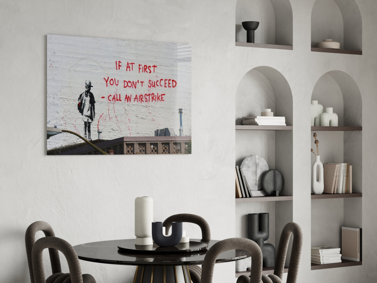Glass art canvas displaying black silhouette figure with red text "If at first you don't succeed - call an airstrike" hanging above dining table.