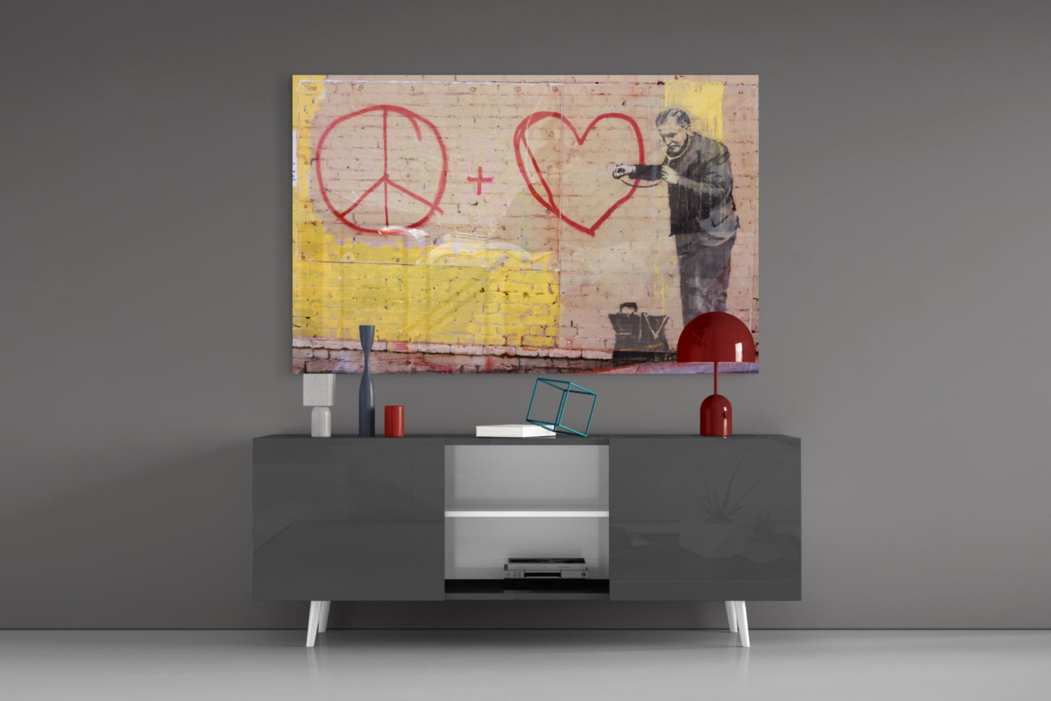 Graffiti Doctor Glass Art mounted above gray media console, depicting stenciled figure with peace symbol and heart outline in red on brick background.