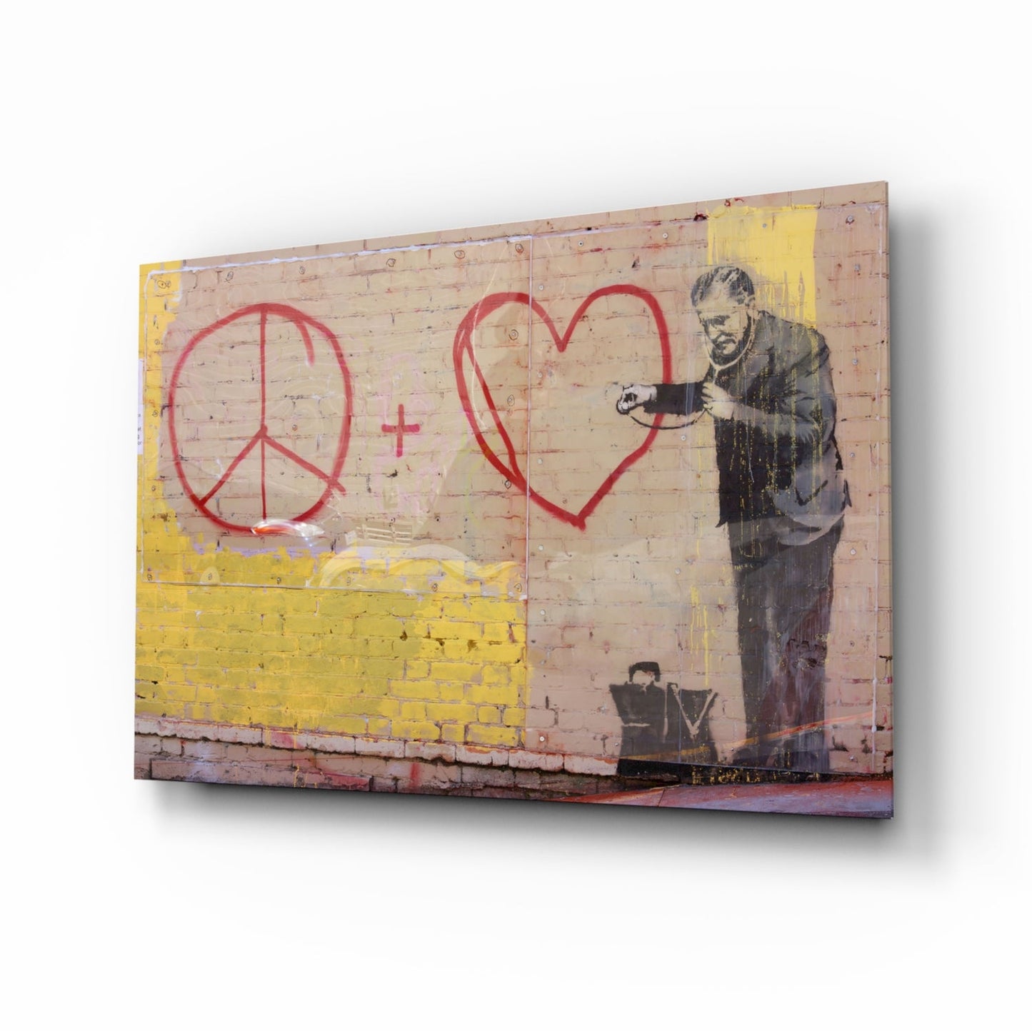 Canvas print of stenciled figure in dark coat drawing red peace sign and heart on pink brick wall with yellow painted section.