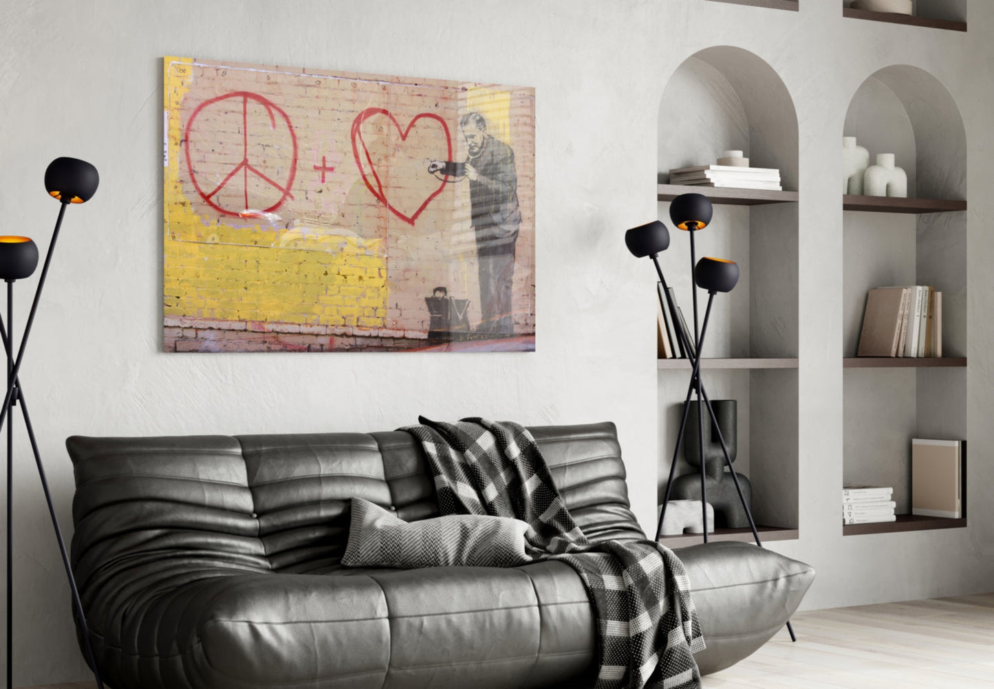 Modern living room with black leather sofa displaying graffiti art print featuring red peace symbol and heart with yellow brick wall.