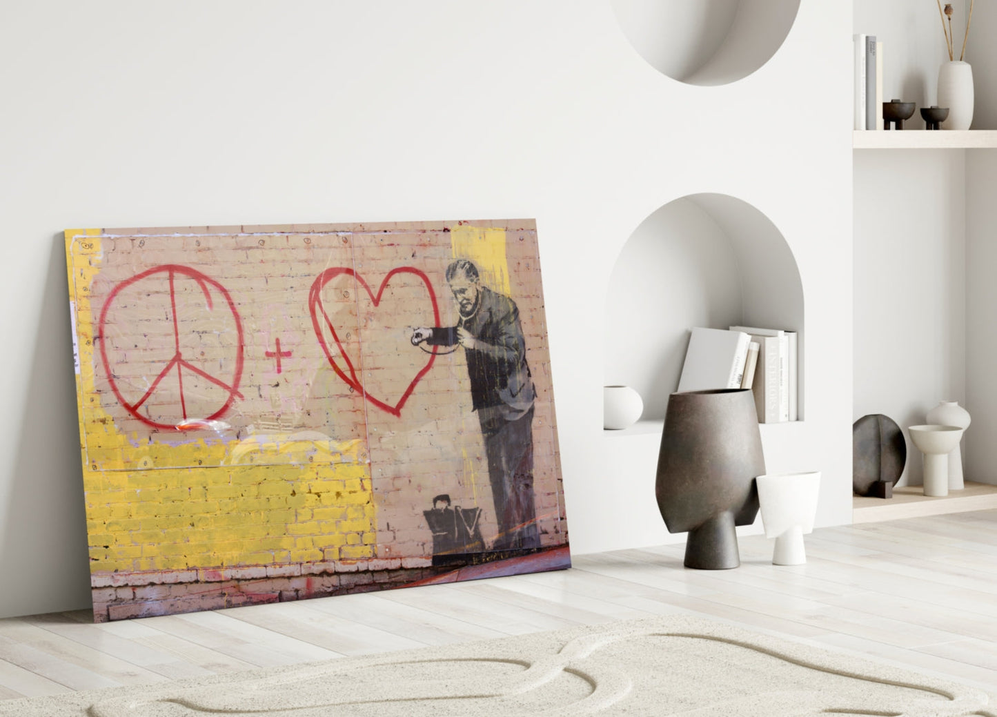 Street art glass panel featuring red peace symbol and heart with stenciled figure leaning right, yellow lower section, displayed against white wall with ceramic vessels.