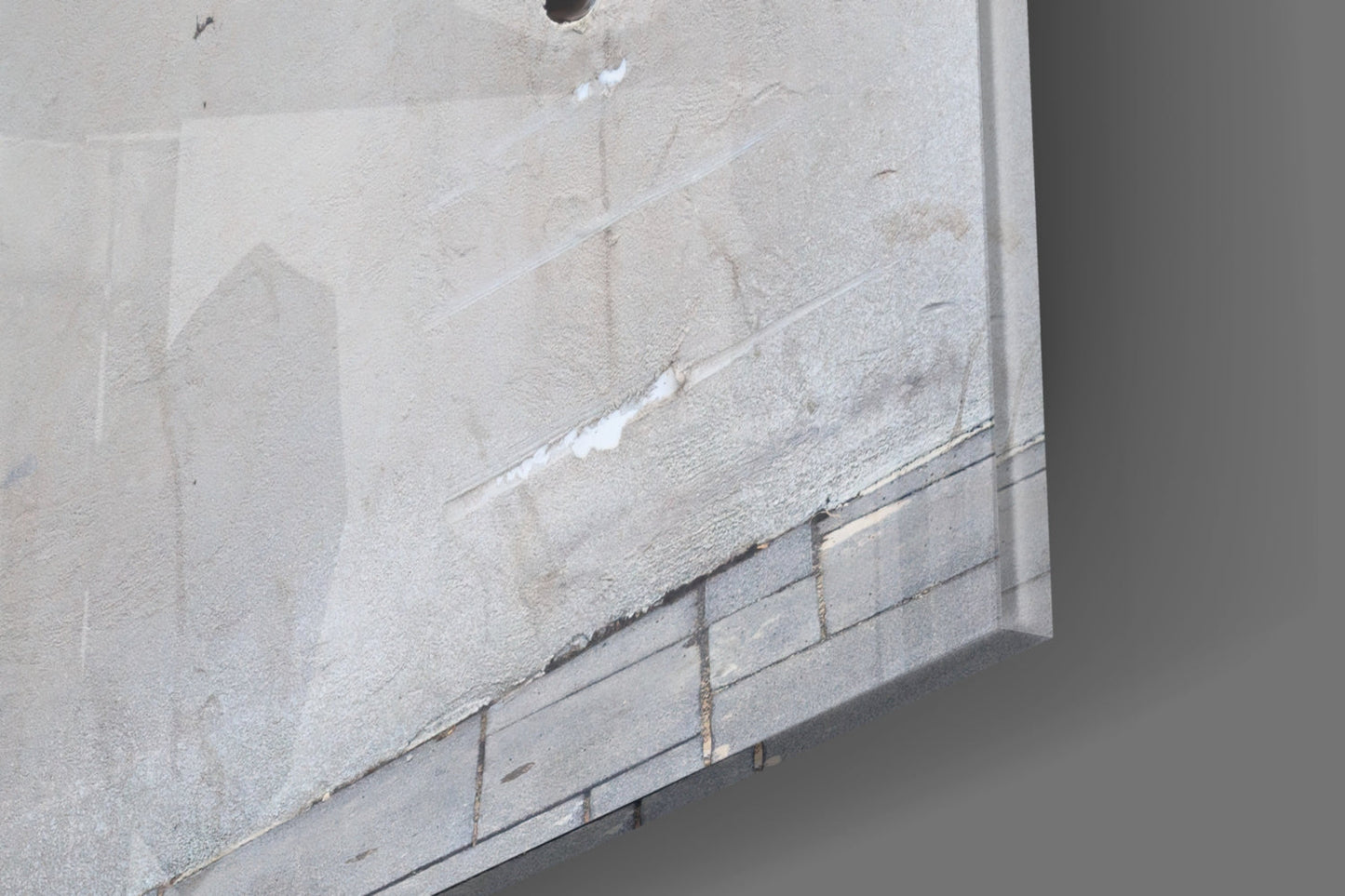 Close-up of concrete wall surface with white painted stripe and metal conduit running diagonally across gray textured cement.