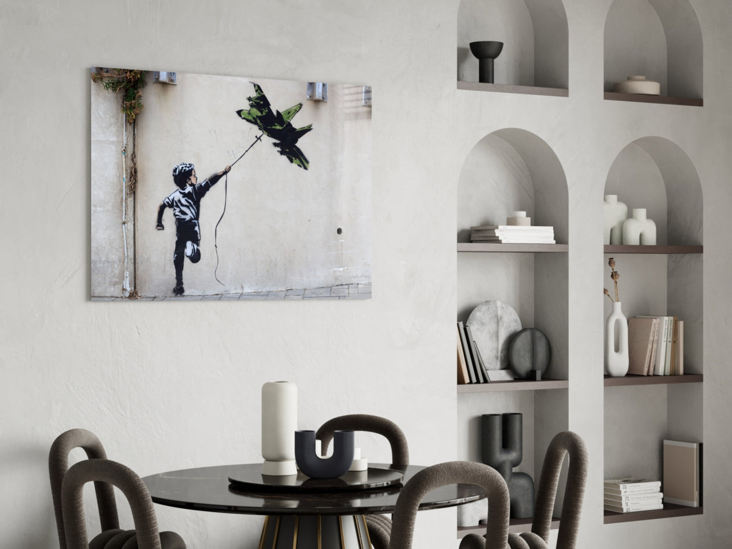 War Kite glass art print displayed on white wall above black round dining table with grey chairs and built-in shelving.